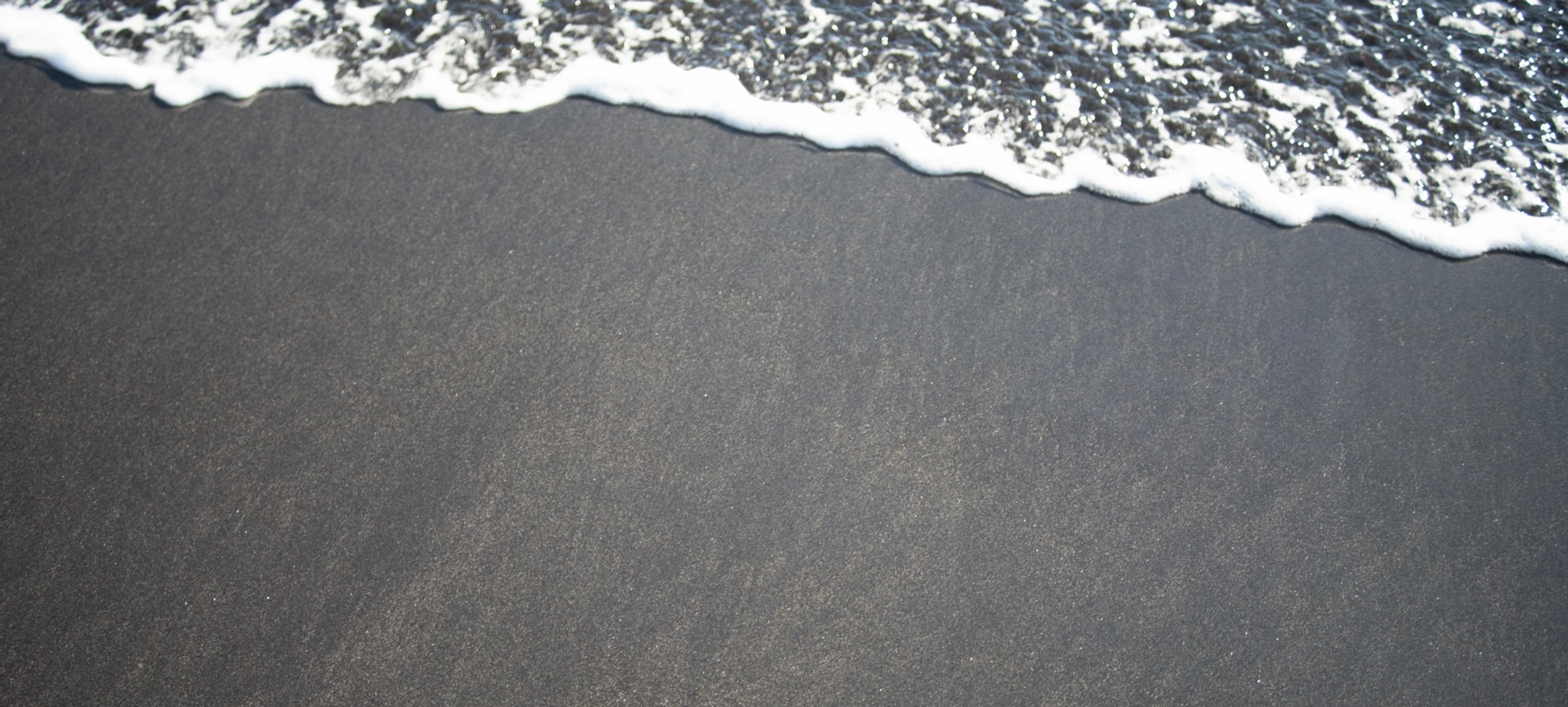 A black sand beach in Iceland with a calm tide